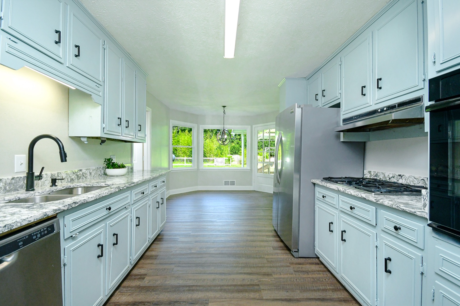 Renovated open kitchen with marble island, custom cabinetry, and bright natural light